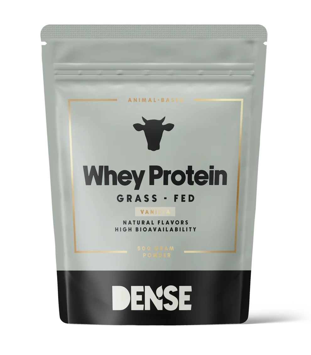 A gray and black pouch of DENSE Grass-Fed Whey Protein Vanilla (500g), animal-based with natural flavors and high bioavailability, features a cow icon on the packaging and contains vanilla-flavored protein powder.