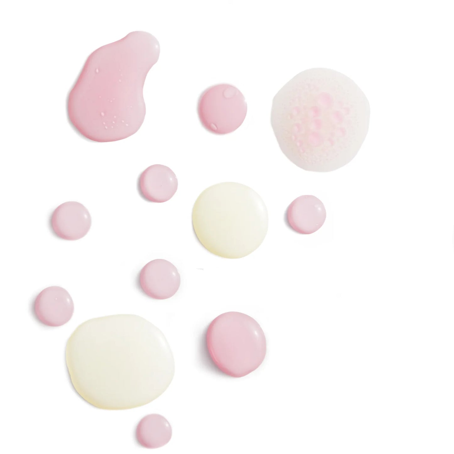 Pink and beige drops of Lumene Nordic-C Arctic Berry Oil-Cocktail by Lumene are scattered on a clean white background, highlighting this Vitamin C skincare product for the ultimate glow.