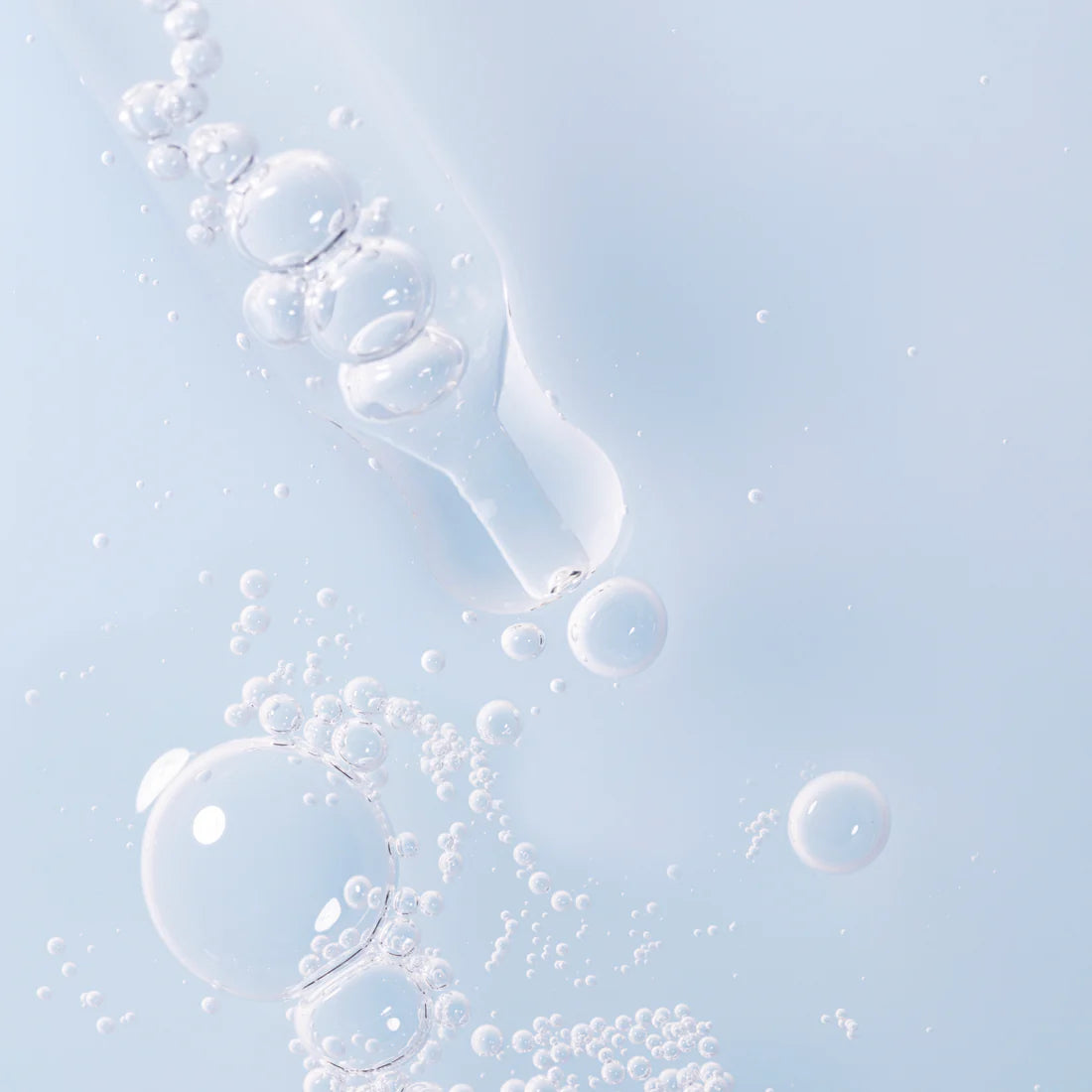 A close-up of a dropper with clear liquid bubbles against a light blue background, evoking the deep hydration and clean aesthetic of Lumene Nordic Hydra Aqua Serum by Lumene.
