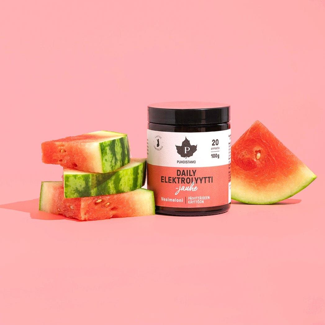 A jar of Puhdistamo Daily Electrolyte Powder Watermelon stands next to three stacked watermelon slices and a large watermelon wedge, all arranged on a pastel pink background.