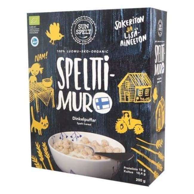 A box of SunSpelt Organic Spelt Cereal features Finnish text, yellow illustrations of a cat, chicken, barn, tractor, and a cereal bowl. The blue and black SunSpelt packaging highlights natural ingredients with white and yellow accents.