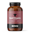 A brown bottle labeled DENSE Beef Organs for HER, a grass-fed beef organ supplement for women's vitality and bone health. Contains 180 capsules (720 mg), black lid, cow head graphic, visible pills, and DENSE brand at the bottom.