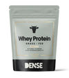 A gray and black pouch of DENSE Grass-Fed Whey Protein Vanilla (500g), animal-based with natural flavors and high bioavailability, features a cow icon on the packaging and contains vanilla-flavored protein powder.