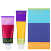 Two colorful tubes from Djusie—one red and purple, the other yellow and blue—stand by the Djusie Dream Team Box, offering moisturizing power fluid and nourishing night treatment formulas.