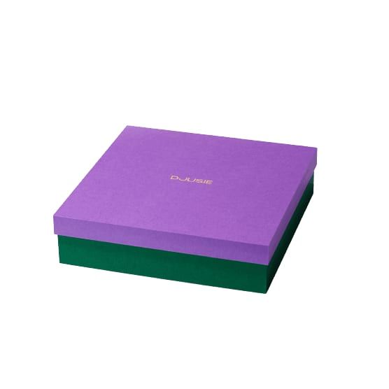 A square green box with a purple lid and gold DJUSIE text on top highlights the Djusie Full Bloom Box Skincare Set by Djusie, ideal for storing skincare products. The box is displayed against a plain white background.