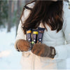A woman in a white winter coat and brown mittens stands in a snowy forest, holding three Foodin Collagen Protein Bars, including the Crunchy Caramel Cinnamon flavor.