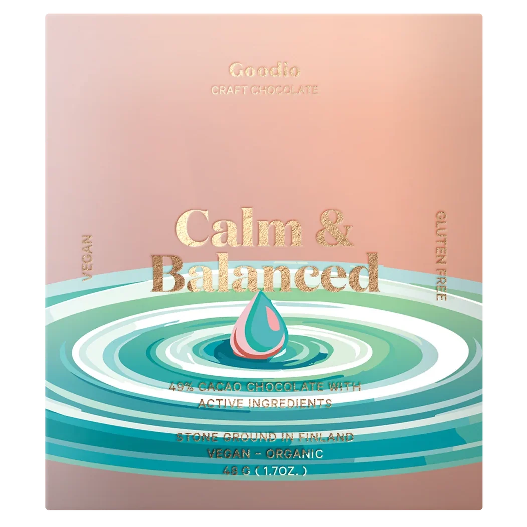 Goodio Calm & Balanced chocolate bar packaging, featuring a soft pink and peach background with gold foil text and a stylized teal and pink droplet over concentric ripples in shades of teal and white.
