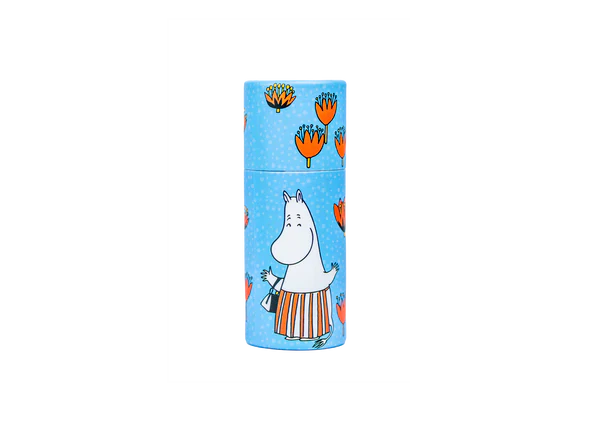 The Gustaf & Linnea Moomin Lipbalm Moominmamma comes in a blue cylindrical container featuring orange flowers and Moominmamma on a polka-dot background, and is an eco-friendly, handmade Swedish lip balm.