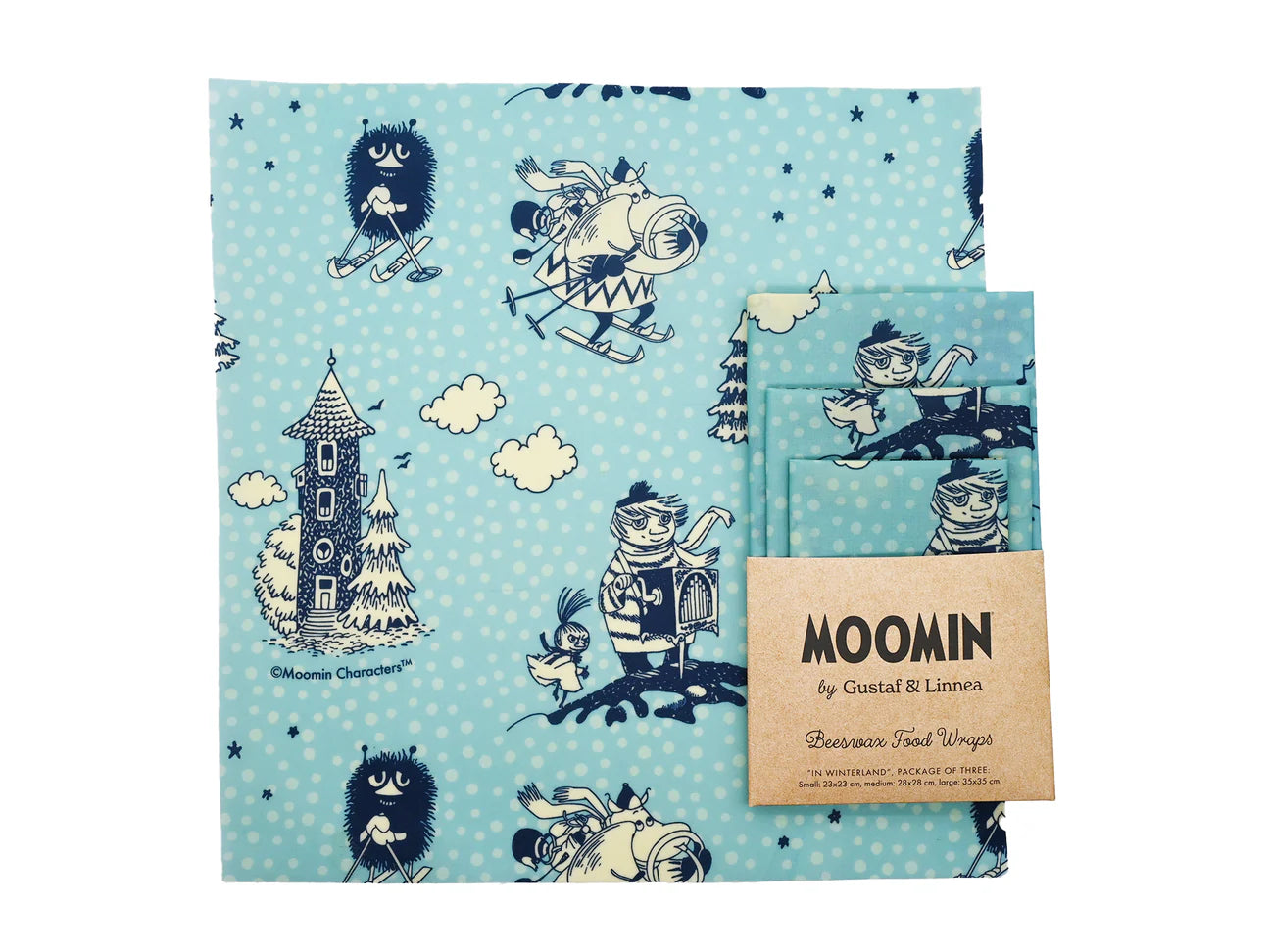 The Gustaf & Linnea Moomin Beeswax Food Wrap features navy Moomin characters skiing, skating, and near a tower on a light blue background with white snowflakes—an eco-friendly, reusable, and charming food storage solution.