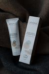 A tube and box of Laponie of Scandinavia Hand Cream Concentrate rest on soft, dark fabric. The fragrance-free, white packaging holds a rich formula by Laponie of Scandinavia, designed to deeply hydrate dry and rough skin.