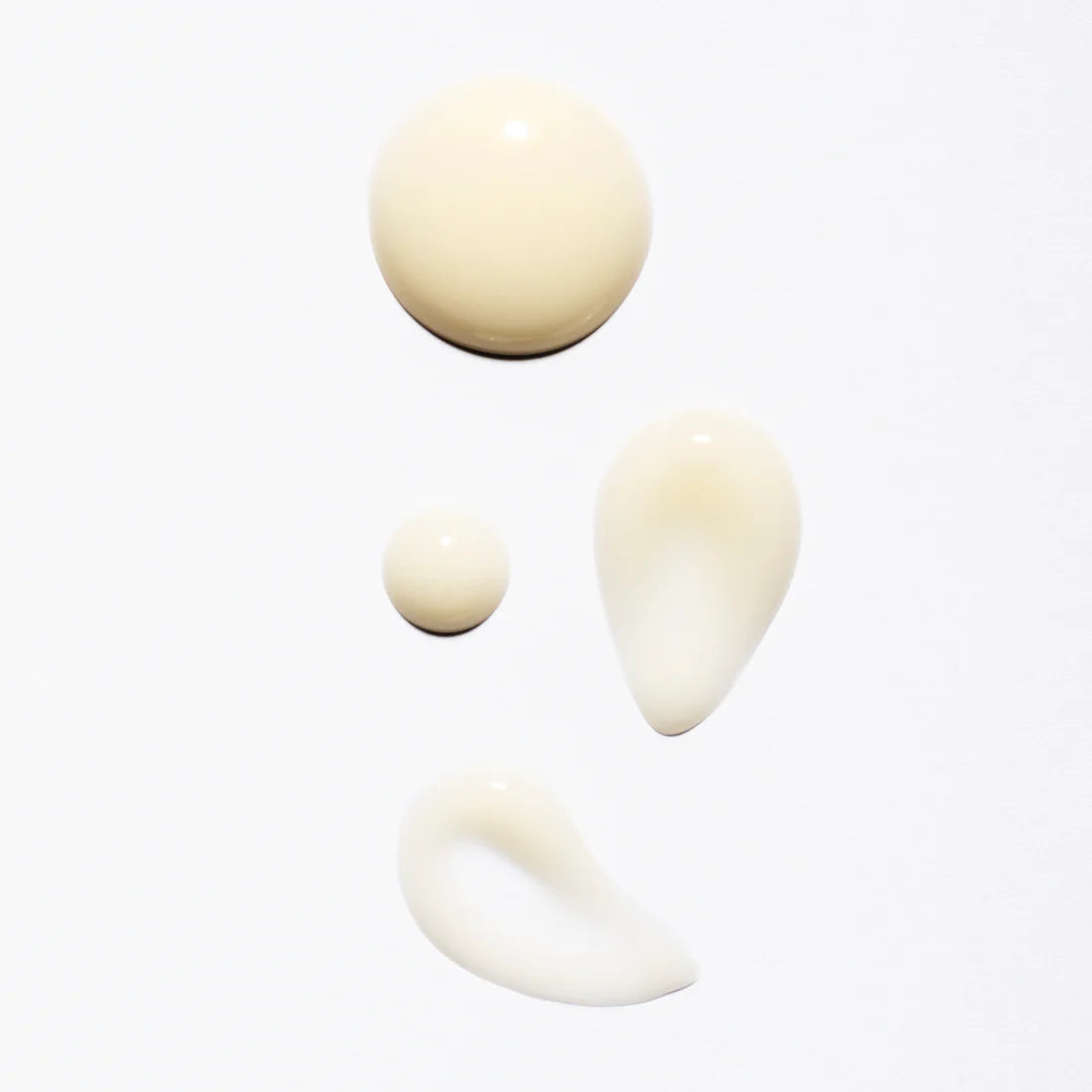 Four drops of Lumene Nordic-C Glow Renew Night Serum, a creamy beige formula with arctic cloudberry and vitamin C, are shown on a white background in various round and teardrop shapes.