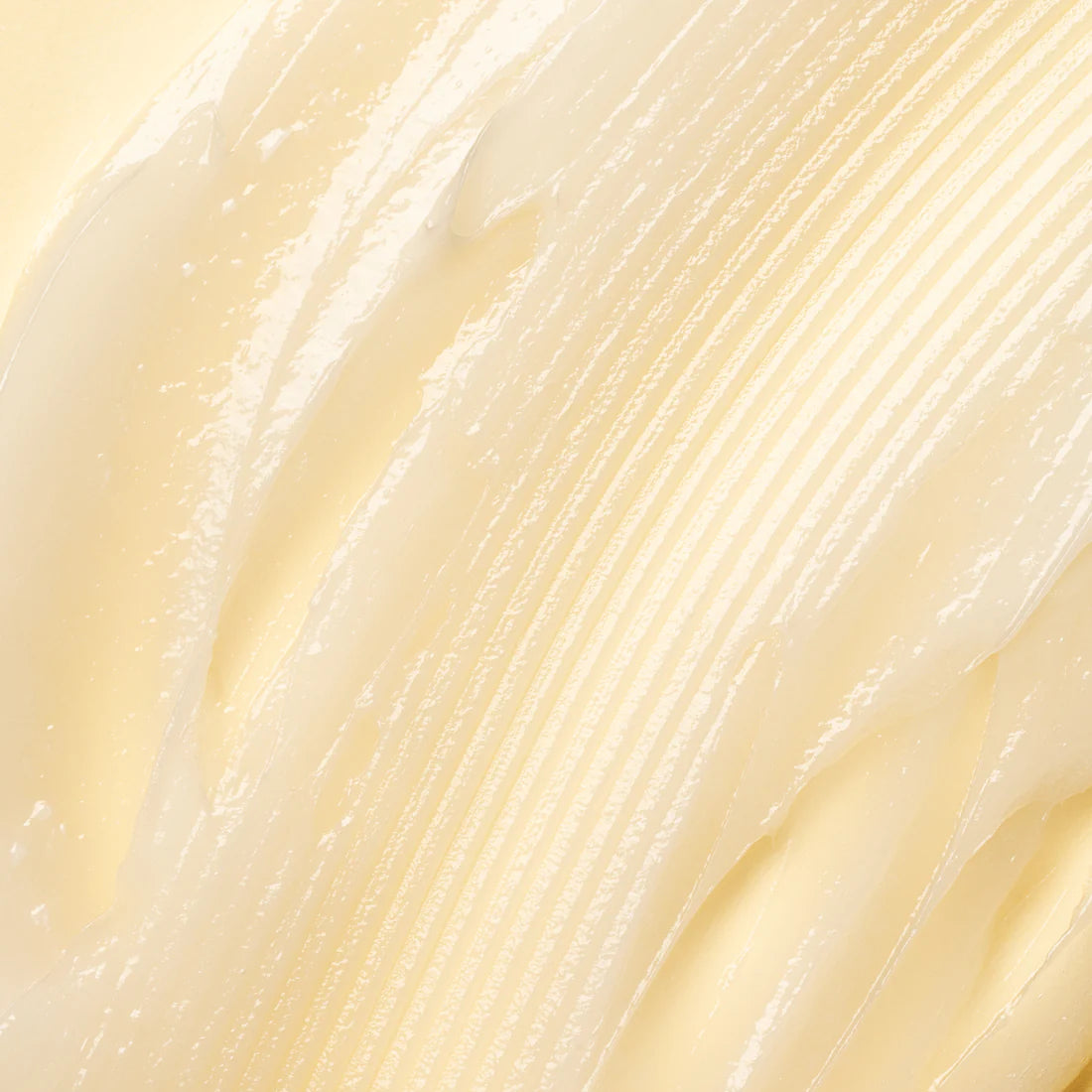 Close-up of Lumene Nordic-C Strength & Shine Conditioner by Lumene—a creamy, light yellow conditioner with a smooth, glossy texture and visible ridges spread on a flat surface.