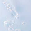 A close-up of a dropper with clear liquid bubbles against a light blue background, evoking the deep hydration and clean aesthetic of Lumene Nordic Hydra Aqua Serum by Lumene.