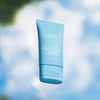 A blue tube of Lumene Nordic Hydra Fresh Hydration Moisturizer SPF50 stands against a soft, blurred blue and white backdrop, creating a fresh, airy look that emphasizes daily hydration from Lumene.