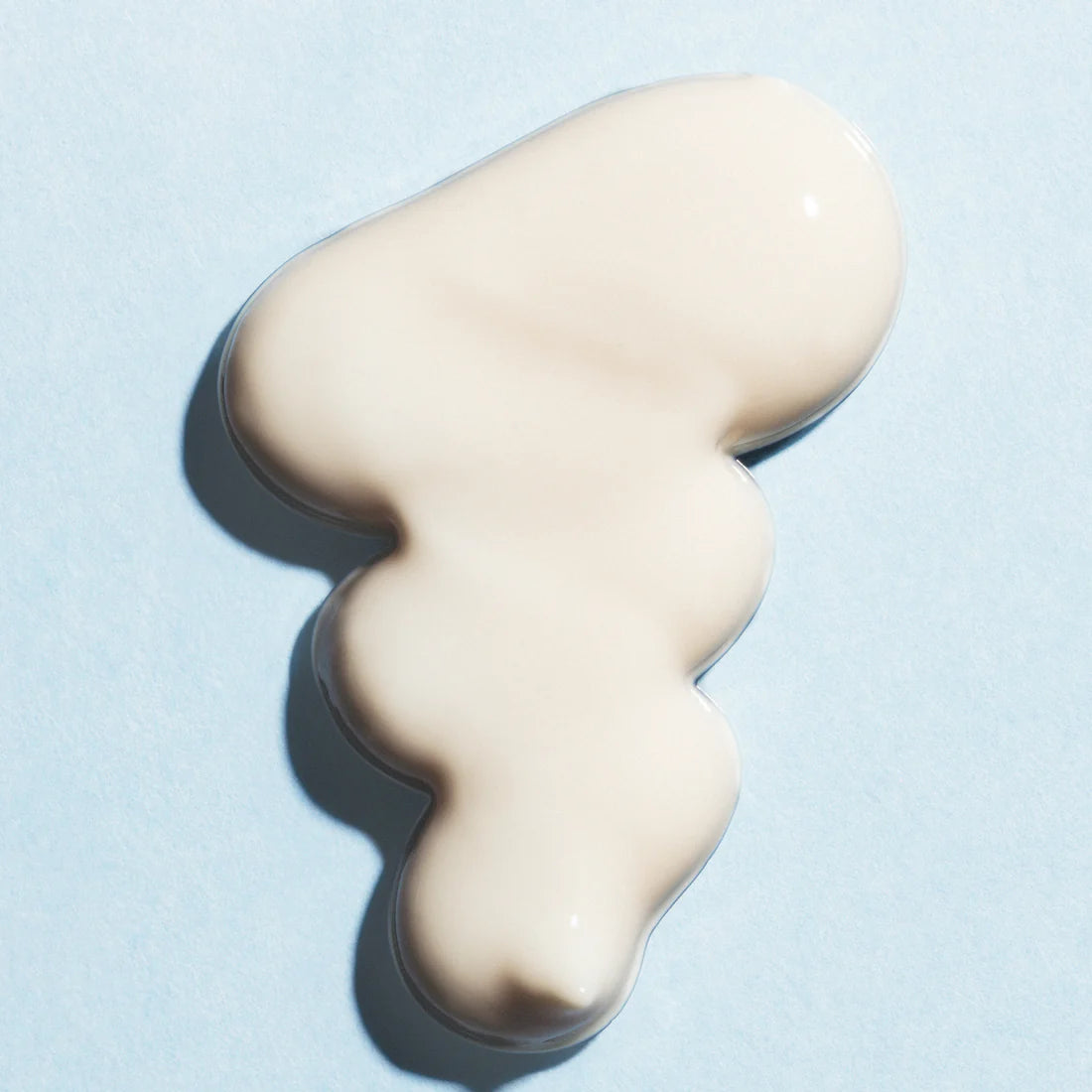A blob of Lumene Nordic Hydra Fresh Hydration Moisturizer SPF50, an off-white cream from Lumene, is spread in an irregular shape on a light blue background.