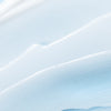 A smooth, light blue and white creamy texture with gentle waves and subtle ridges, like Lumene Nordic Hydra Moisture Conditioner by Lumene spread across a surface.