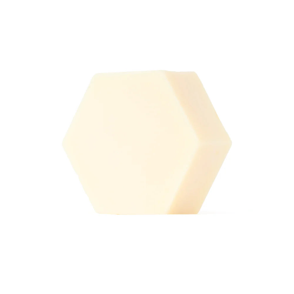 Luonkos Hydrate Essence Hand & Body Soap by Luonkos is a pale, cream-colored hexagonal bar made with natural plant oils—ideal as a fragrance-free body soap for sensitive skin, shown against a plain white background.