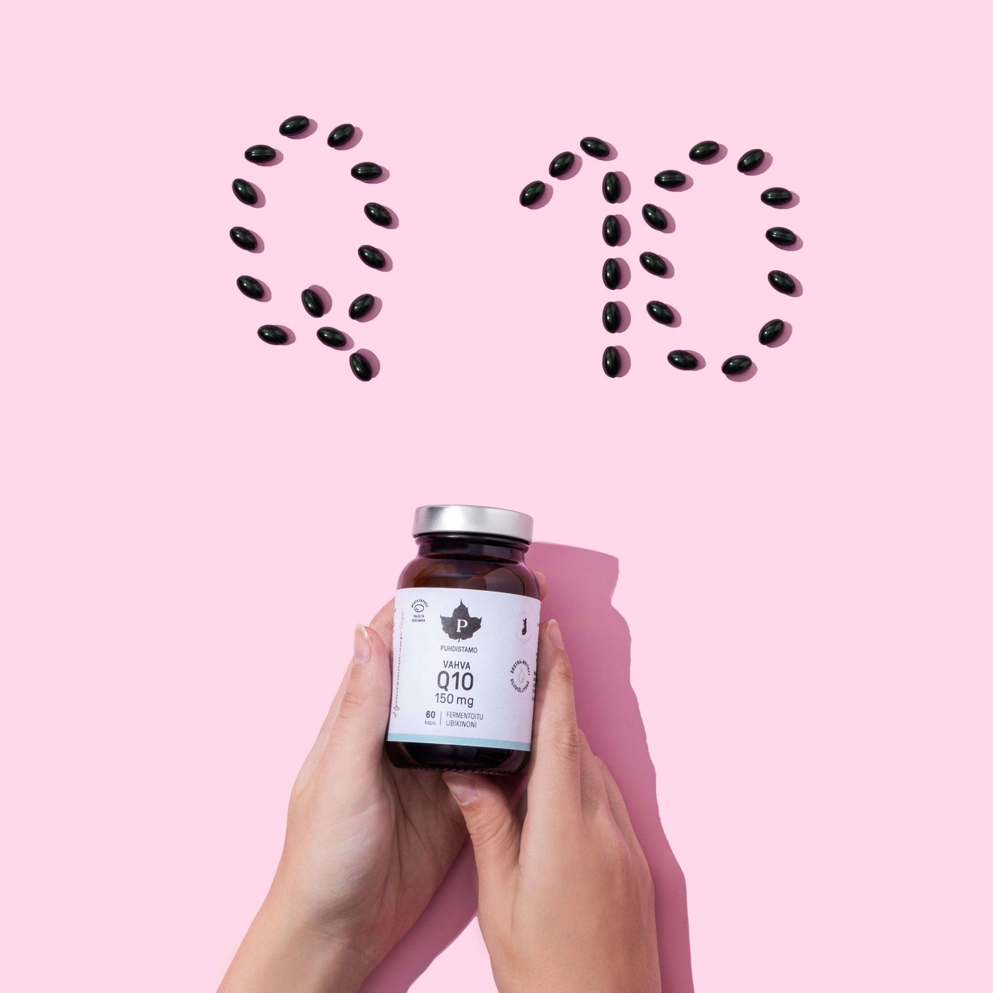 Two hands hold a Puhdistamo High-Strength Q10 Ubiquinone 150 mg bottle; above, black capsules on pink spell "Q10," highlighting Puhdistamo’s role in supporting energy metabolism with this potent ubiquinone supplement.