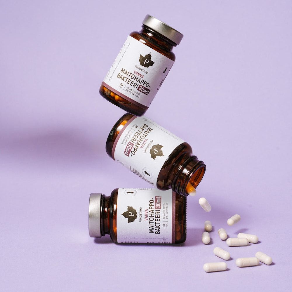 Three bottles of Puhdistamo Strong Probiotic 30 Billion CFU stand stacked against a light purple background, with white capsules nearby—ideal for supporting gut health and immunity.