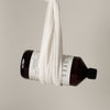 A dark brown SEES Company bottle labeled "SEES 2-in-1 Laundry Detergent with Vinegar" is wrapped in a white cloth and suspended against a plain, light background.