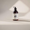 A brown pump bottle labeled SEES Hand Wash No. 1 Cedar & Orange by SEES Company stands on a neutral background with soft shadows, featuring a minimalist label with dark blue shapes and black text.