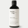 A black 100ml bottle of sauna/ing Sauna Scent Spruce & Grape from Finland features Nordic fragrance, coordinates and ingredients on the label, plus a black screw cap.