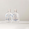Two clear glass SEES x Moomin Room Diffuser Nordic Summer bottles by SEES Company, each with a cork stopper and blue floral and character designs—an enchanting Moomin-inspired room diffuser evoking Nordic summer.