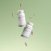 Two white bottles labeled "THERA Nordic Move" float against a soft green gradient with capsules suspended around them, highlighting this THERA Nordic magnesium supplement that supports healthy bowel movements in a clean, minimalist scene.