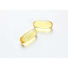 Two translucent yellow Möller Double Omega-3 gel capsules from Möller, rich in omega-3 fatty acids, rest on a white surface, spaced slightly apart and casting faint shadows.