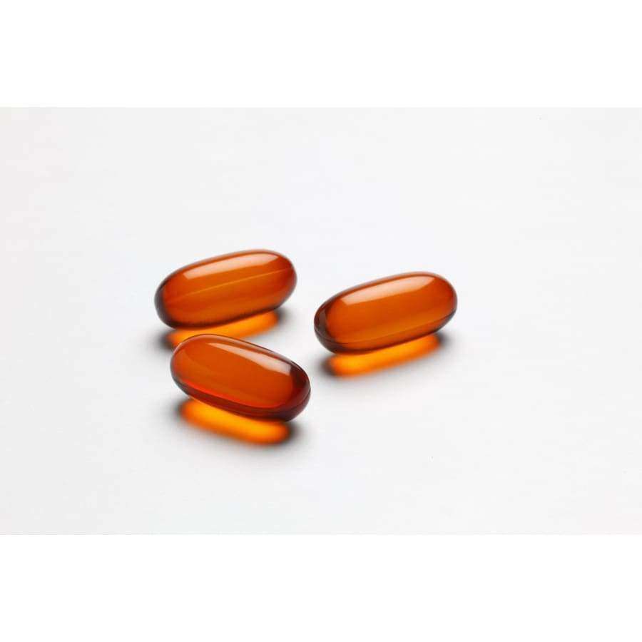 Three translucent, oval-shaped orange gel capsules of Möller Omega-3 Heart from Möller are arranged on a white surface, spaced apart with soft shadows beneath each.