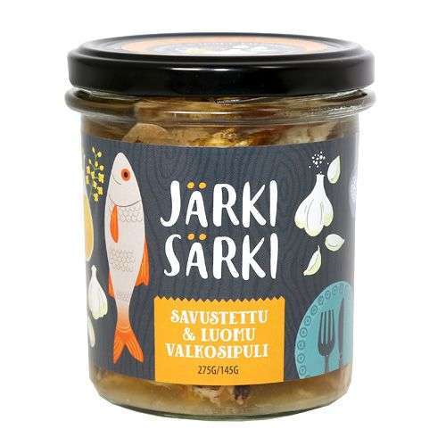 A glass jar of Järki Särki Smoked with Organic Garlic, topped with a black lid and an illustrated label featuring a fish, garlic bulbs, and Finnish text. Made from sustainably caught wild fish by Järki Särki.
