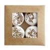A brown cardboard box with a clear window displays four round white Kaurilan Sauna Grapefruit Footbath bombs—a vegan product handmade in Helsinki.