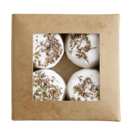 A brown cardboard box with a clear window displays four round white Kaurilan Sauna Grapefruit Footbath bombs—a vegan product handmade in Helsinki.