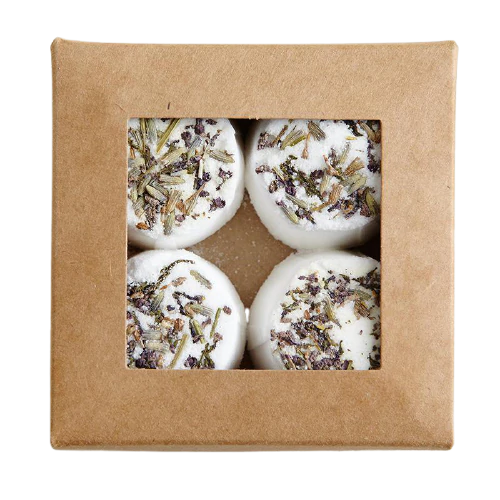 The Kaurilan Sauna Lavender Footbath by Kaurilan Sauna comes in a brown box with a clear window, showing four round white vegan bath bombs topped with dried lavender and arranged in a 2x2 grid.
