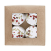 A brown cardboard box with a clear window displays four round Kaurilan Sauna Peppermint Footbath bombs, each topped with dried herbs and petals—handmade in Helsinki by Kaurilan Sauna using natural cosmetics.