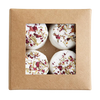 A brown cardboard box with a clear window showcases four round Kaurilan Sauna Rosemary Footbath bombs, handmade in Helsinki from natural cosmetics and topped with dried flower petals and herbs.