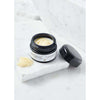 A black jar of Laponie of Scandinavia All-Around Balm sits open on a white marble surface, with some gentle cream for sensitive skin spread nearby and another marble slab in the background.