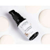 A bottle of Laponie of Scandinavia Brightening Treatment Serum with a pump dispenser sits on a white surface, surrounded by round swatches of cream—perfect for targeting uneven skin tone.
