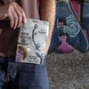 Someone holds a pack of Renjer Nordic Reindeer Jerky Sea Salt from Renjer in front of a graffiti-covered wall on rocky ground, highlighting the distinct flavor of Lapland reindeer meat in an urban environment.