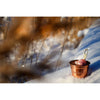 The Emendo Stove Cup & Himalaya Salt rests on snowy ground outdoors, holding a piece of ice. In the background, blurred dry grass suggests the refreshing allergy relief from sauna steam with Emendo’s quality product.