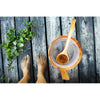 Sandy bare feet on weathered planks rest beside a wooden bucket and ladle, with an Emendo Sauna Fragrance (Eucalyptus, Birch, Smoke Sauna & Tar) set to fill the air with refreshing scents and essential oils.