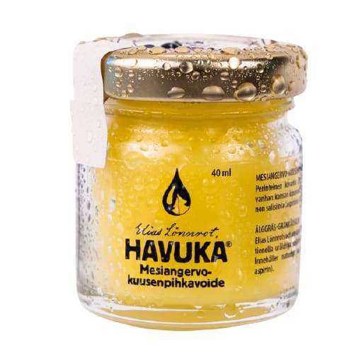 A small clear jar of Havuka Meadowsweet Spruce Resin Balm features a gold lid, water droplets, Finnish text, and the black droplet logo. This natural pain relief balm is by Havuka and has a yellow color.