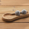 Two smooth, gray Hukka Solejoy massage balls by Hukka sit on a footprint-shaped cork base, displayed on a wooden surface.