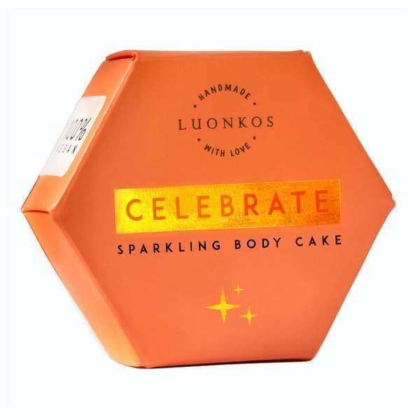 The Luonkos Celebrate Body Cake comes in an orange hexagonal box with gold lettering and star details. Infused with sea-buckthorn oil, this handmade treat gives your skin a radiant glow. Packaging reads "Handmade with love.