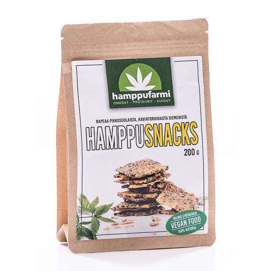 A brown paper package labeled Nordic Hempfarm HempSnacks shows stacked seed crackers. Green text and a hemp leaf logo emphasize these vegan, 100% natural, light-salted snacks from Nordic Hempfarm, with a net weight of 200 grams.